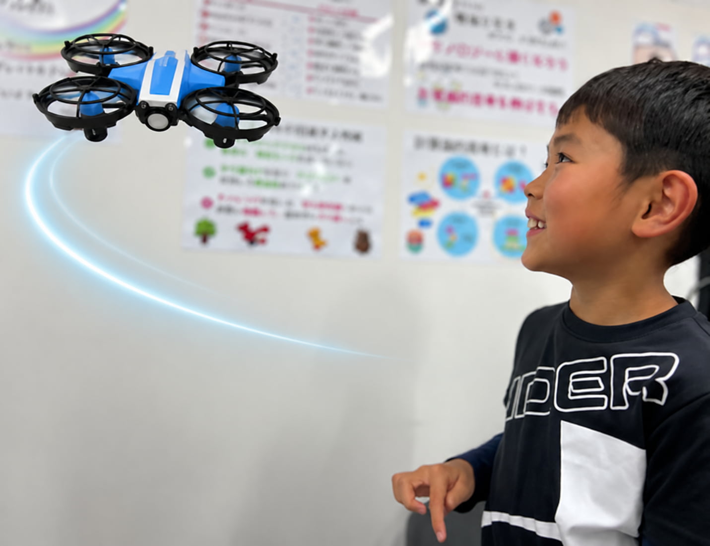 自分のプログラムで飛ぶドローンを見上げる子ども