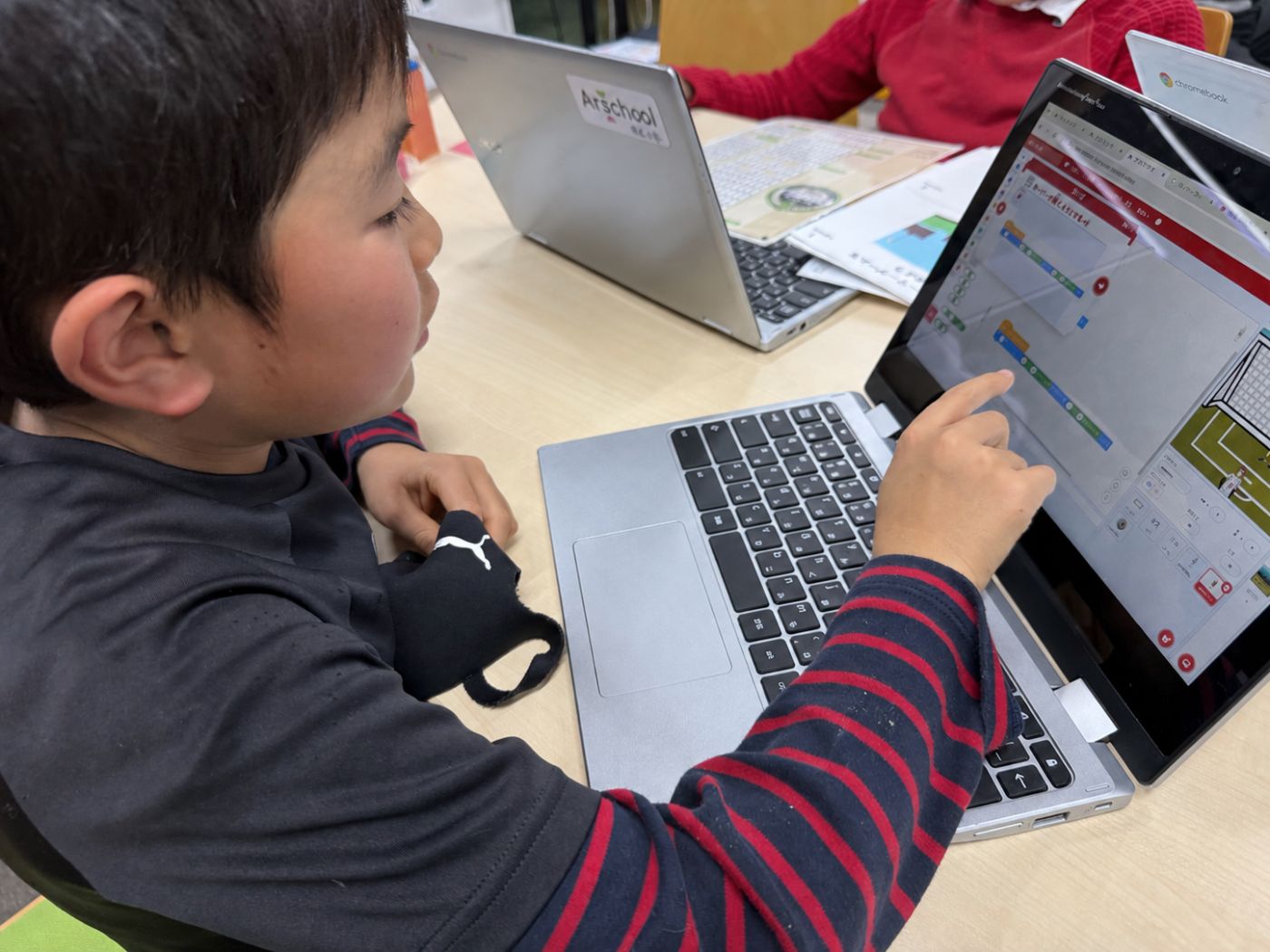 Scratchの画面に集中して創作する子ども